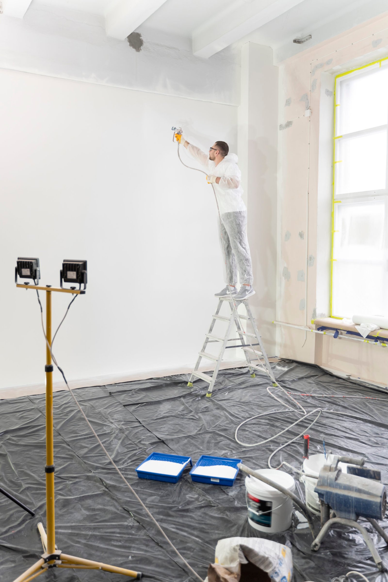 worker-painting-wall-ladder-full-shot